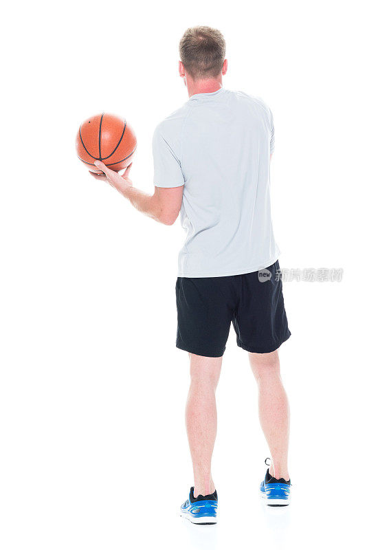 全身/一人/一人/后视图20-29岁英俊的人棕色头发/短发白人男性/年轻男子运动员/运动员/篮球运动员站在白人背景前，拿着篮球